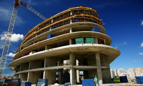 pexels-photo-1463917-1463917 Low angle view of a circular building under construction with a crane, clear blue sky.